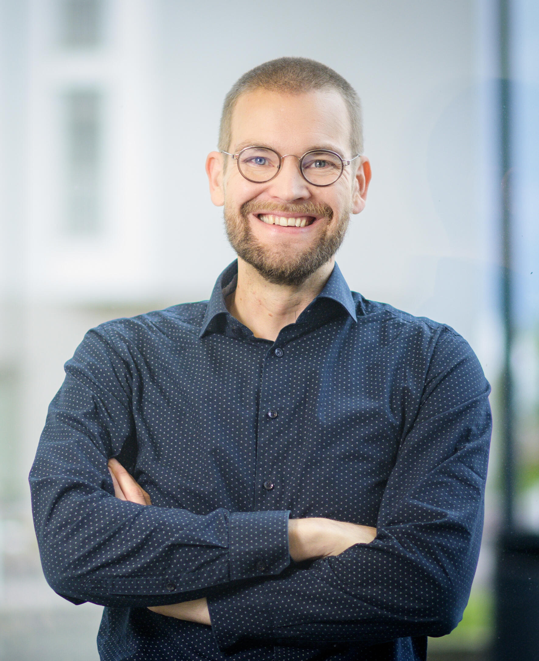 Eetu Niemi – Kokonaisarkkitehti, konsultti ja kirjailija Portrait of Eetu Niemi, enterprise architecture consultant and author, wearing a dark blue shirt and smiling confidently at the camera.